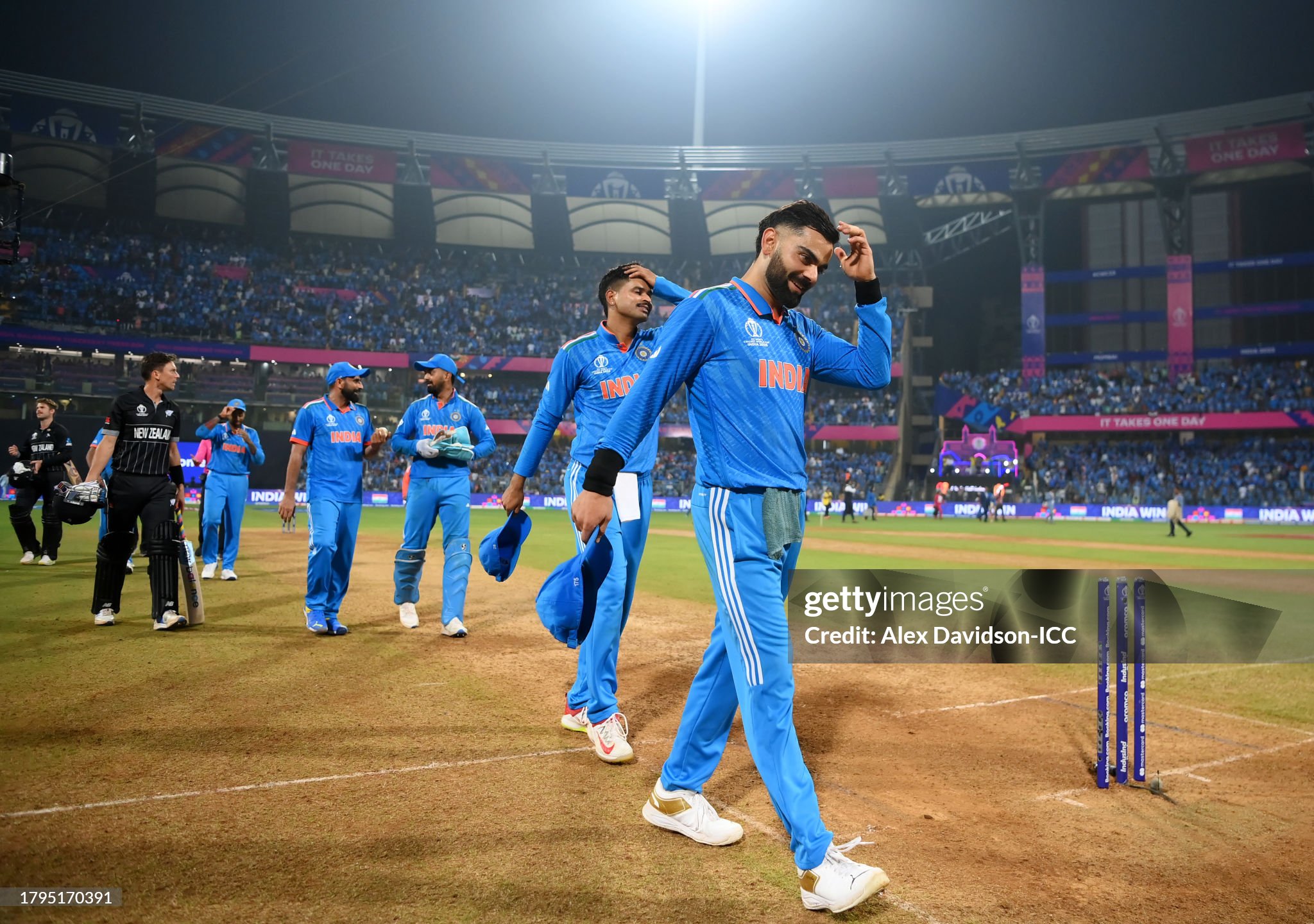 Virat Kohli smiling with hand in hair in post-match walkoff with ample negative space
